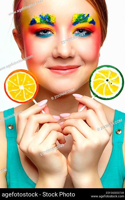 Teenager girl with unusual face art make-up . Child with lollipops in hands. Sweet tooth concept