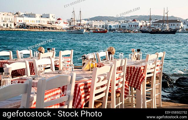 Empty chairs and dining tables in a traditional Greek at the beach restaurant at famous island of Mykonos in Greece