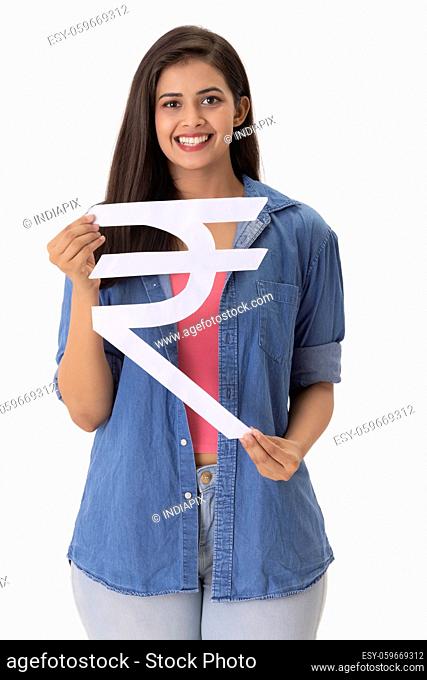 A young woman holding Indian rupee symbol made of cardboard in hand