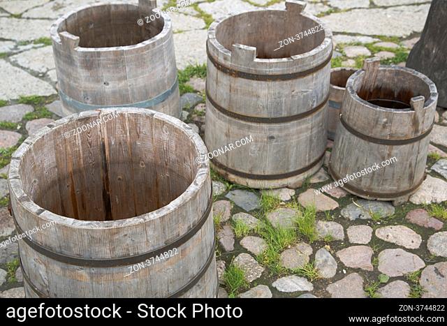 Four empty water barrels on stony yard floor