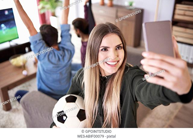 Female soccer fan taking a selfie at home