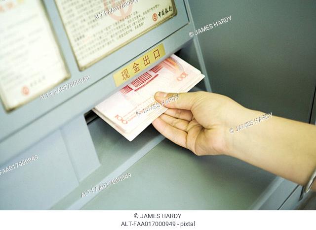 Person taking banknotes from ATM machine, cropped view