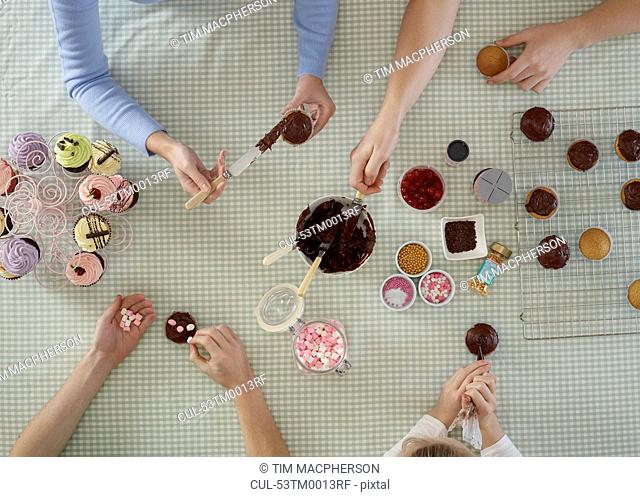 Overhead view of people decorating cakes