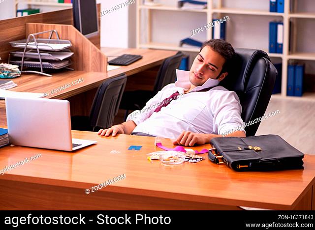 Young drug addicted male employee sitting at workplace
