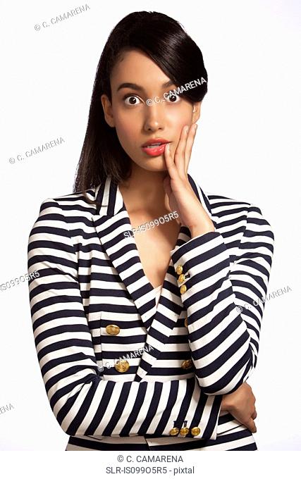 Young woman in striped top looking shocked against white background