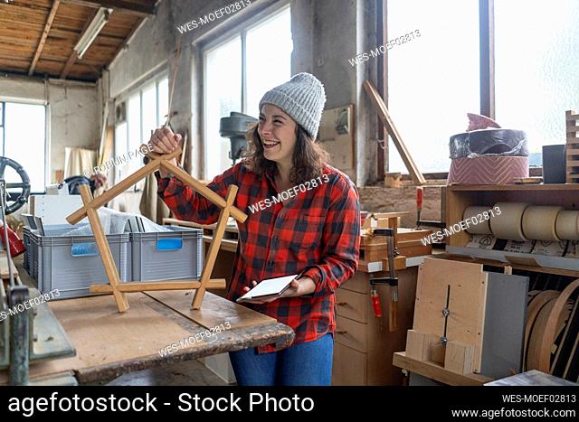 Happy carpenter holding workpiece in her workshop