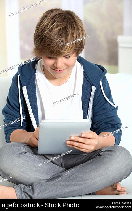 Young teen boy using electronic tablet at home