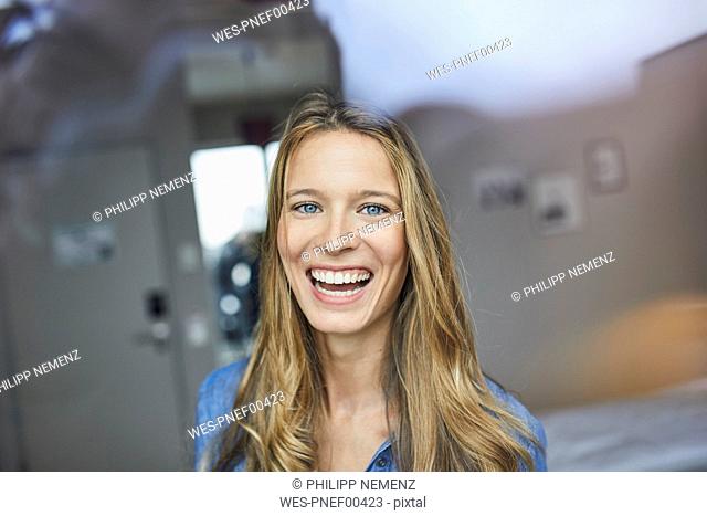 Portrait of laughing young woman behind windowpane