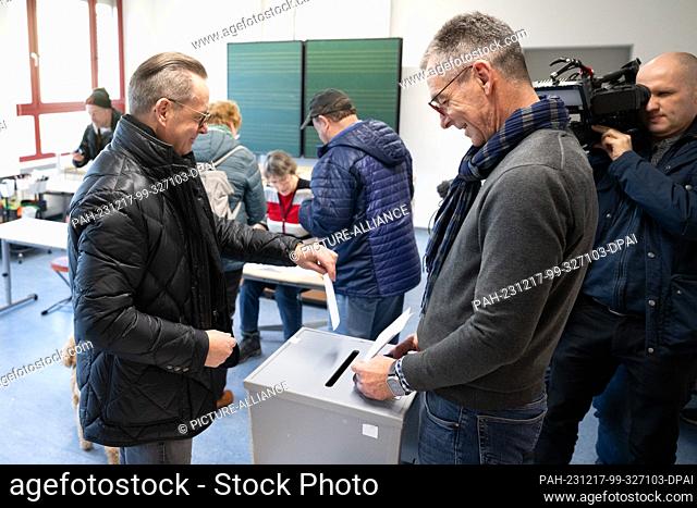 17 December 2023, Saxony, Pirna: Ralf Thiele (Free Voters, l), candidate for mayor, casts his ballot in a ballot box at a polling station in an elementary...