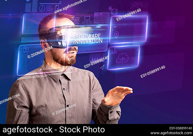 Businessman looking through Virtual Reality glasses with SOFTWARE INNOVATION inscription, new technology concept