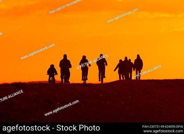 14 April 2023, Lower Saxony, Wangerooge: 11.04.2023, Wangerooge. Walkers and cyclists are on the East Frisian island Wangerooge in the evening in the backlight...