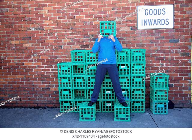 Man on crates, covering his face