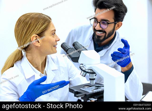 Male scientist working with microscope, doctor's team in laboratory doing research, man and woman making scientific experiments