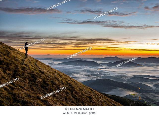Italy, Umbria, Apennines, hiker standing on Monte Acuto watching sunrise