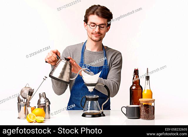 Barista, cafe worker and bartender concept. Portrait of handsome young male employee making filter coffee pouring water in kettle smiling tenderly