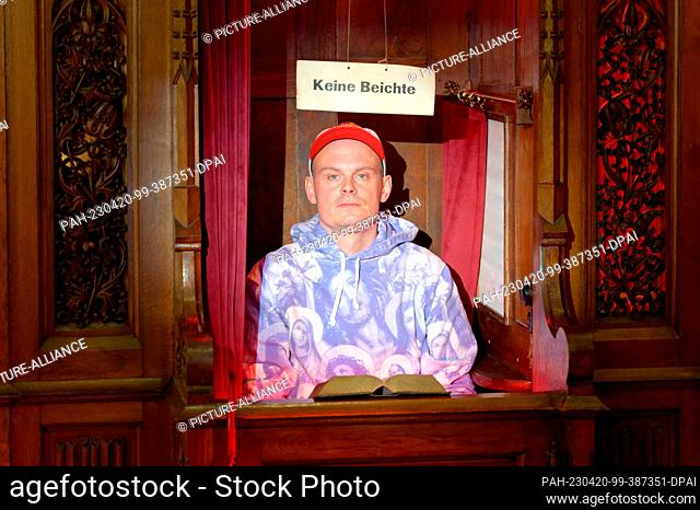 PRODUCTION - 20 April 2023, North Rhine-Westphalia, Cologne: The artist Dennis Josef Meseg sits in a confessional in his art action