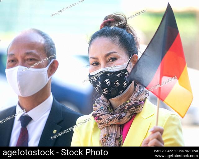22 April 2020, Saxony, Dresden: Two members of the Vietnamese community stand in front of a senior citizens' residence in Dresden with a small German flag