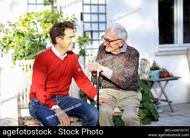 Smiling man talking with father in backyard