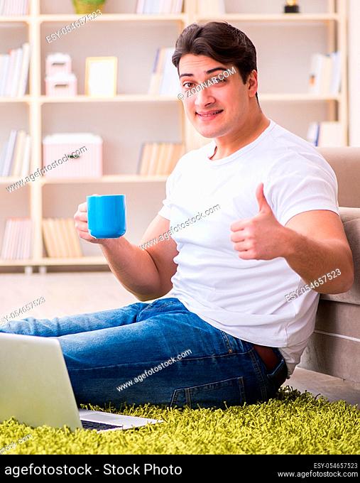 The man working on laptop at home on carpet floor