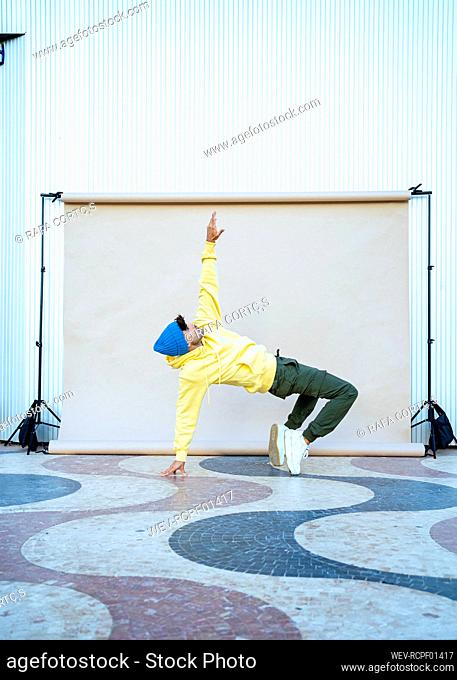 Young male performer balancing while dancing on floor by backdrop