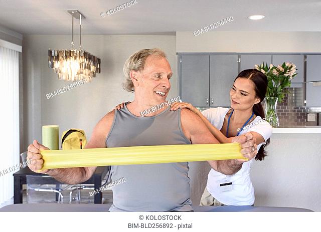 Physical therapist helping man using resistance band