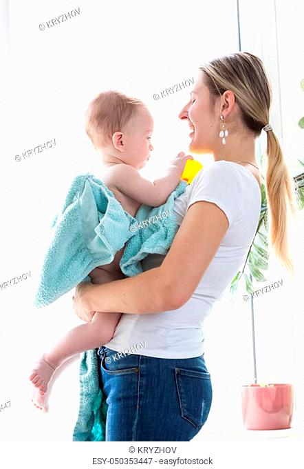 Happy young mother with baby boy after bathing