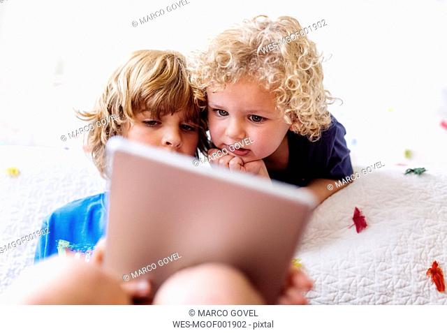 Two little brothers using tablet at home
