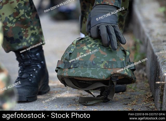 11 May 2022, Bavaria, Hammelburg: A recruit being trained for the reserve takes his helmet at the German Army's Hammelburg training area