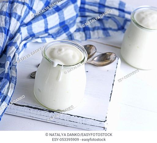 homemade yogurt in a glass jar on a white wooden board, close up, top view