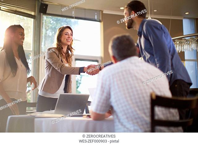 Two people greeting each other at a business meeting in a restaurant