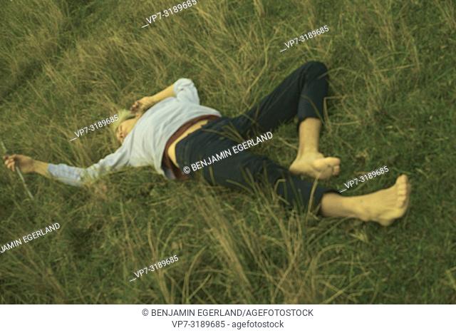 young man lying in meadow, nature, nature bonding, back to nature, lost, resting, exchausted, exhaustion, relaxing, escaping daily life, escaping, depression