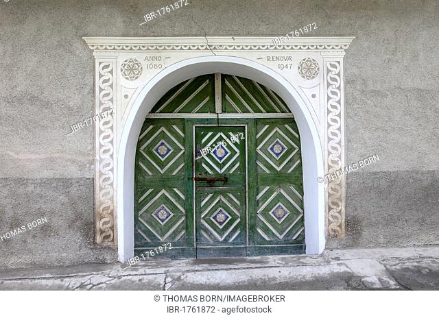 Green gate with historic wood carvings in Vna, Lower Engadine, Grisons, Switzerland, Europe