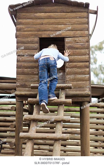 Smiling boy climbing into playhouse