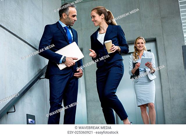 Business colleagues talking to each other while walking down stairs