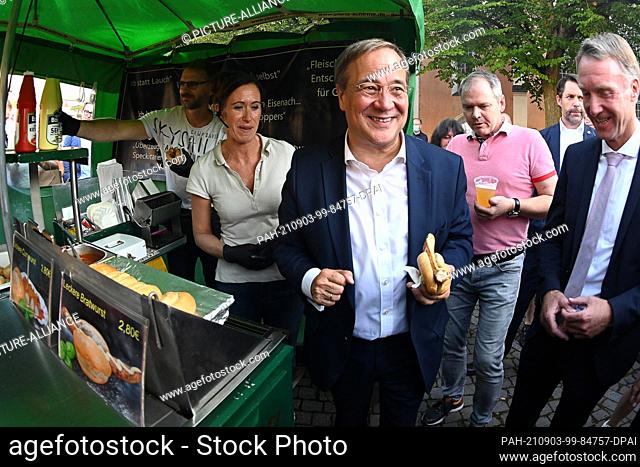 03 September 2021, Thuringia, Eisenach: Chancellor candidate Armin Laschet (M, CDU) stands with a bratwurst in a roll at an election campaign event on the...