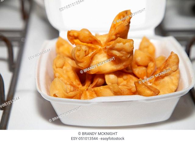 A stack of crab rangoons in a carryout box