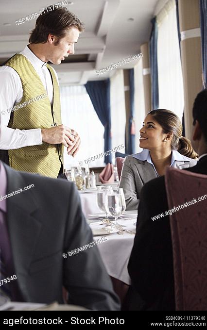 Waiter taking businesswoman's order at a restaurant