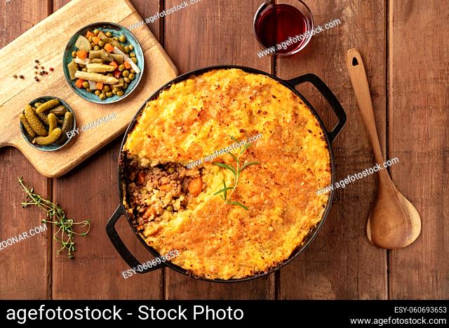 Shepherd's pie with pickles, herbs, and red wine, shot from above on a dark rustic wooden background