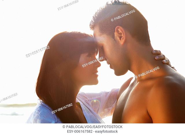 portrait of a passionate couple in love kissing and embracing between backlit