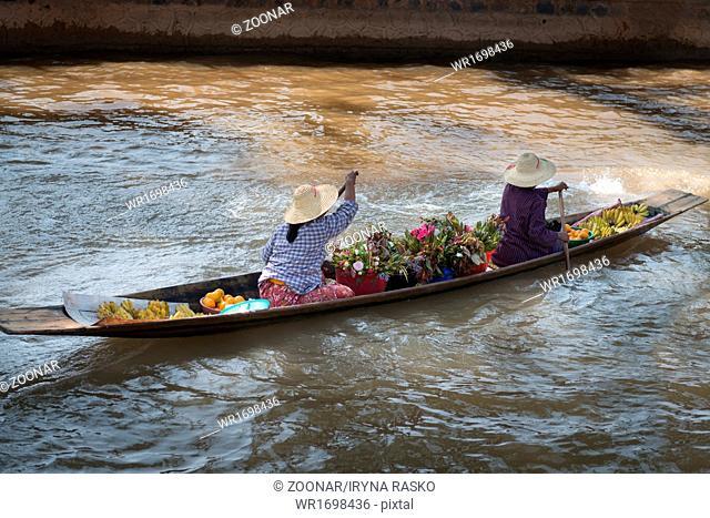 Floating asian vendors on long wooden boat
