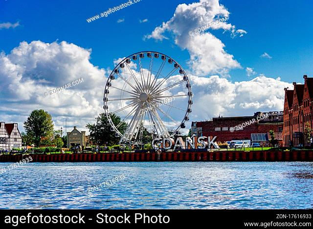 Danzig, Poland - 2 September, 2021: ferris wheel and historic buildings with city sign on the Motlawa River in the Old Town of Danzing
