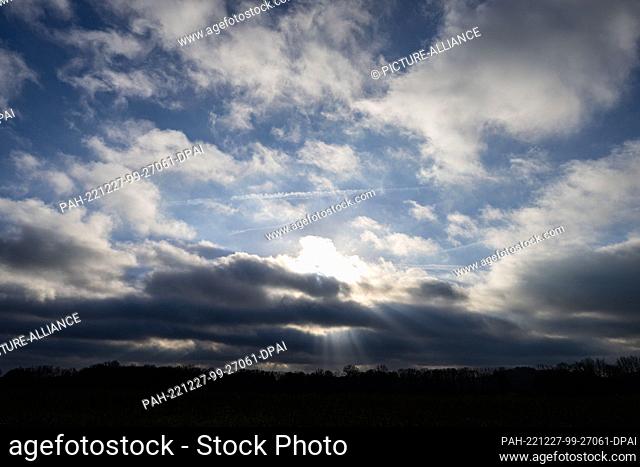 27 December 2022, North Rhine-Westphalia, Warendorf: The sun shines through white-gray clouds and blue sky. Photo: Guido Kirchner/dpa