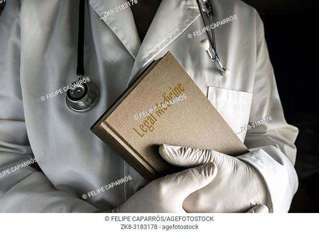 Doctor holds book of legal medicine, conceptual image