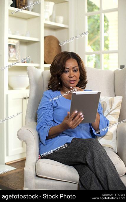 Middle aged black female at home Using tablet to have video call