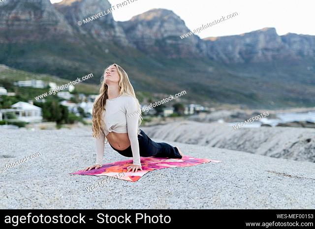 Young woman in cobra pose in front of mountain range