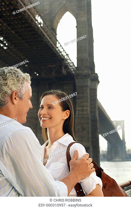 Couple embracing under Brooklyn Bridge