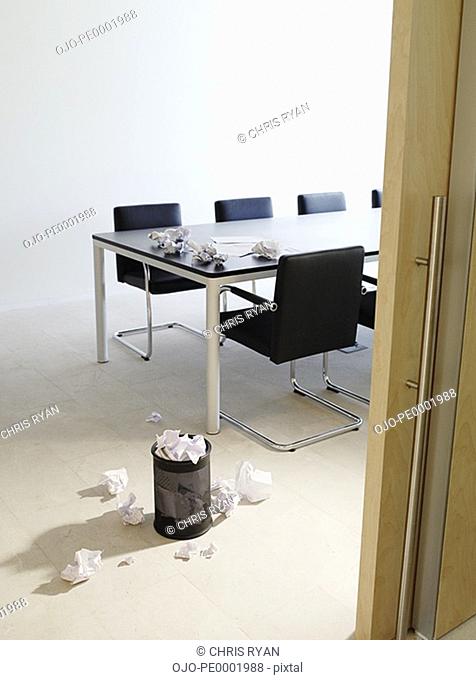 Empty boardroom littered with crumpled papers