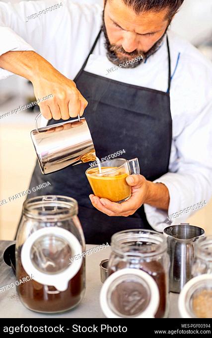 Chef pouring milk while working in commercial kitchen at restaurant