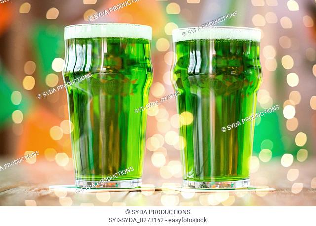 two glasses of green beer on wooden table