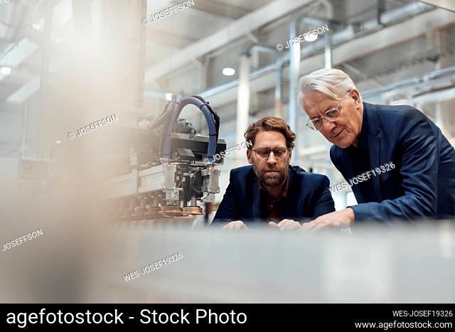 Senior businessman having discussion with colleague in factory